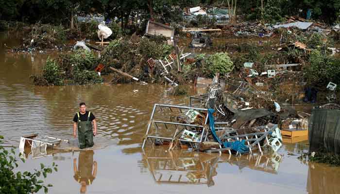 A man walks through the water in an area affected by floods following heavy rainfalls in Bad Neuenahr-Ahrweiler, Germany, July 15, 2021. — Reuters/Wolfgang Rattay