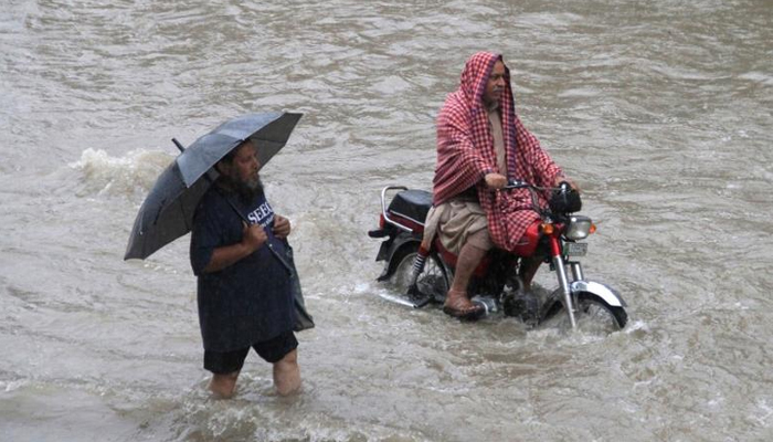 A man holds an umbrella as he walks through floodwaters during heavy rain in Lahore, Pakistan, July 3, 2018. — Reuters/File
