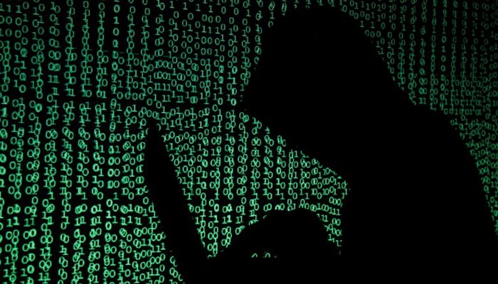 A hooded man holds a laptop computer as cyber code is projected on him in this illustration picture taken on May 13, 2017. — Reuters/File