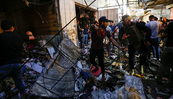 A man picks up debris as Iraqi security forces inspect the site of an explosion in Sadr City district of Baghdad, Iraq July 19, 2021. — Reuters