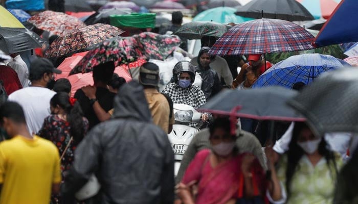 A woman rides a scooter through a crowded market on a rainy day amidst the spread of the coronavirus disease (COVID-19) in Mumbai, India, on July 14, 2021. — Reuters/File