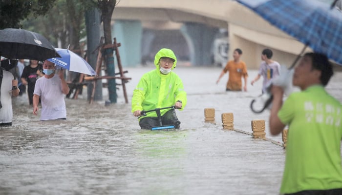 This photo taken on July 20, 2021 shows a man riding a bicycle through flood waters along a street following heavy rains in Zhengzhou in China´s central Henan province. — AFP/File