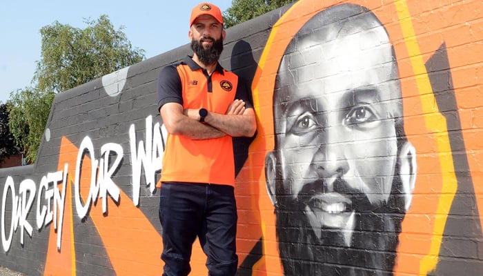 England cricketer Moeen Ali stands beside his mural painted at Spark Green park in Birmingham. — Photo by author