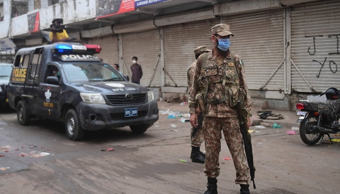 Army personnel and policemen arrive at a market to enforce an evening lockdown imposed amid rising COVID-19 coronavirus cases in Karachi on July 28, 2021. — AFP/File
