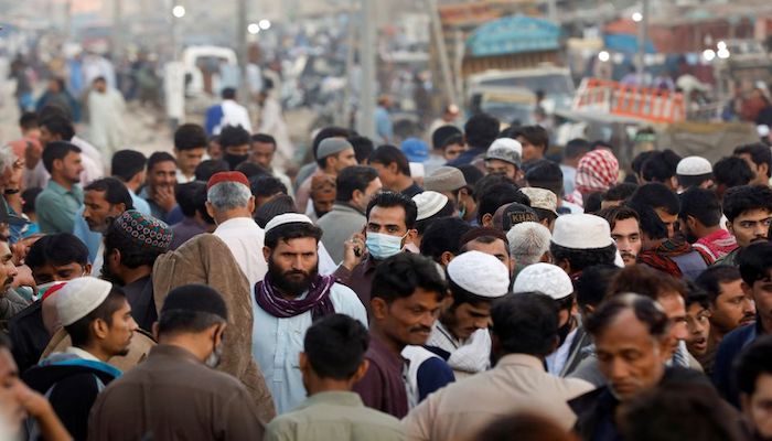 A man wearing a protective mask walks through a crowd of people along a makeshift market as the outbreak of the coronavirus disease (COVID-19) continues in Karachi. Photo: Reuters