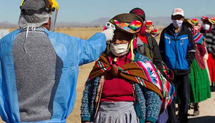 A health worker checks the temperature of residents from surrounding communities heading to the weekly food market in Coata, Peru, on July 8, 2020. — AFP