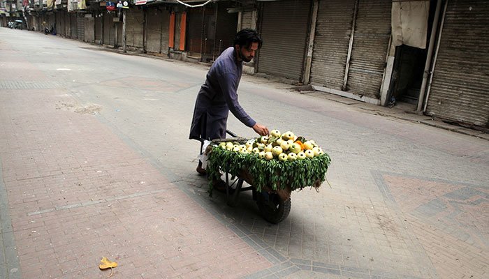 Man standing on an empty street vegetable pull cart. Photo: File