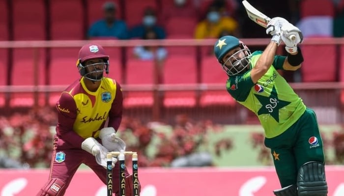 Pakistan batsman Mohammad Rizwan smashes the ball for a six as the West Indies wicketkeeper looks on. Photo: AFP