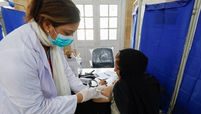 Image showing a masked healthcare worker administering the COVID-19 vaccine to a woman. File photo.