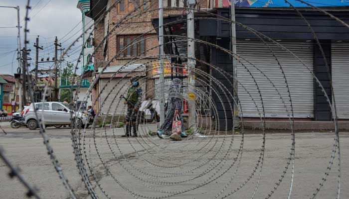 A woman walks past a concertina barricade erected by the Indian security forces during restrictions imposed on the eve of Martyrs Day in old city of Srinagar, Indian Occupied Kashmir (IoK). July 13 is observed as Martyrs Day to pay homage to the 22 civilians killed in firing by Dogra Army outside Srinagar Central Jail in 1931.