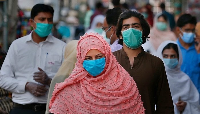 Image showing several people wearing masks walking on a street. Photo: File
