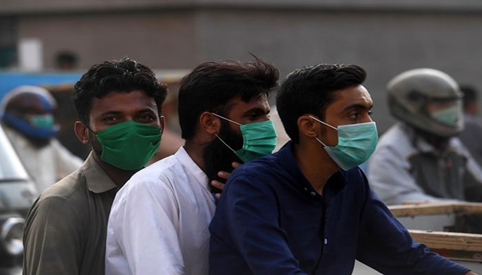 Three men wearing facemasks, picture on a motorcycle. Photo: AFP