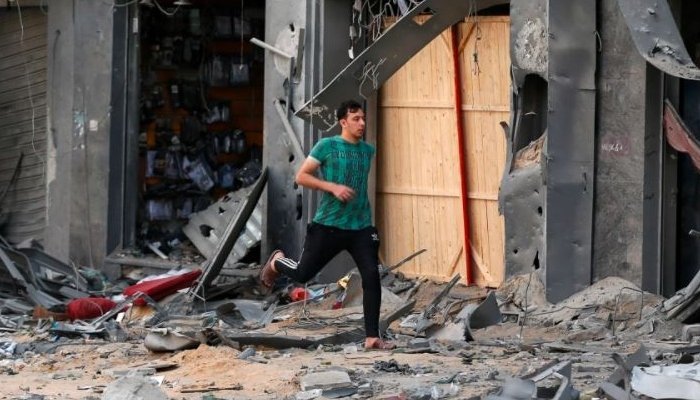 A Palestinian man runs for cover during an Israeli air attack near the site of a destroyed tower building in Gaza City. Photo: Reuters