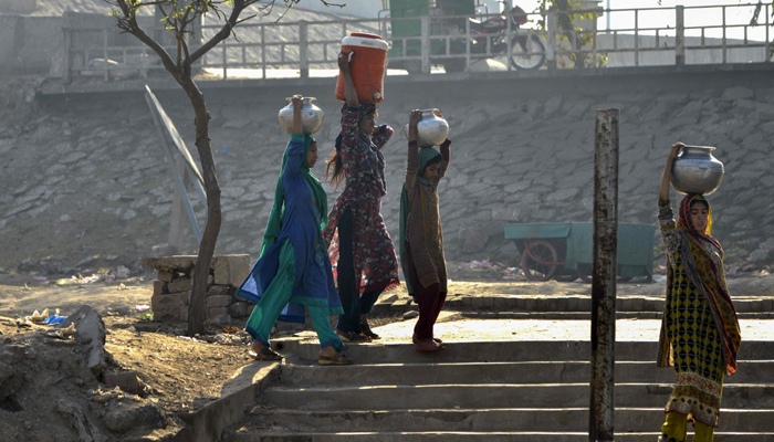 In this picture taken on February 26, 2018, shows Pakistani residents carrying pots filled with drinking water from a handpump on the outskirts of Lahore. Photo: AFP