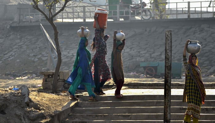 In this picture taken on February 26, 2018, shows Pakistani residents carrying pots filled with drinking water from a handpump on the outskirts of Lahore. Photo: AFP