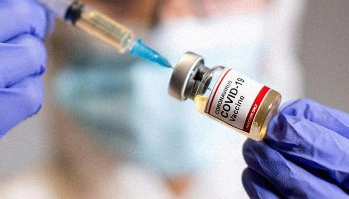 A woman holds a small bottle — labeled Coronavirus COVID-19 Vaccine — and a medical syringe, October 30, 2020. Photo: Reuters