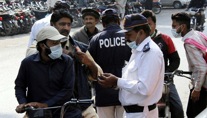 Traffic police staff issuing challan to people riding bikes without a helmet at Zainab Market in Karachi February 04, 2021. — PPI/File