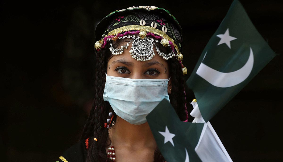 A girl poses for a picture with flags of Pakistan at the tomb of national poet Allama Mohammad Iqbal during Pakistans 75th Independence Day celebrations in Lahore on August 14, 2021. — AFP