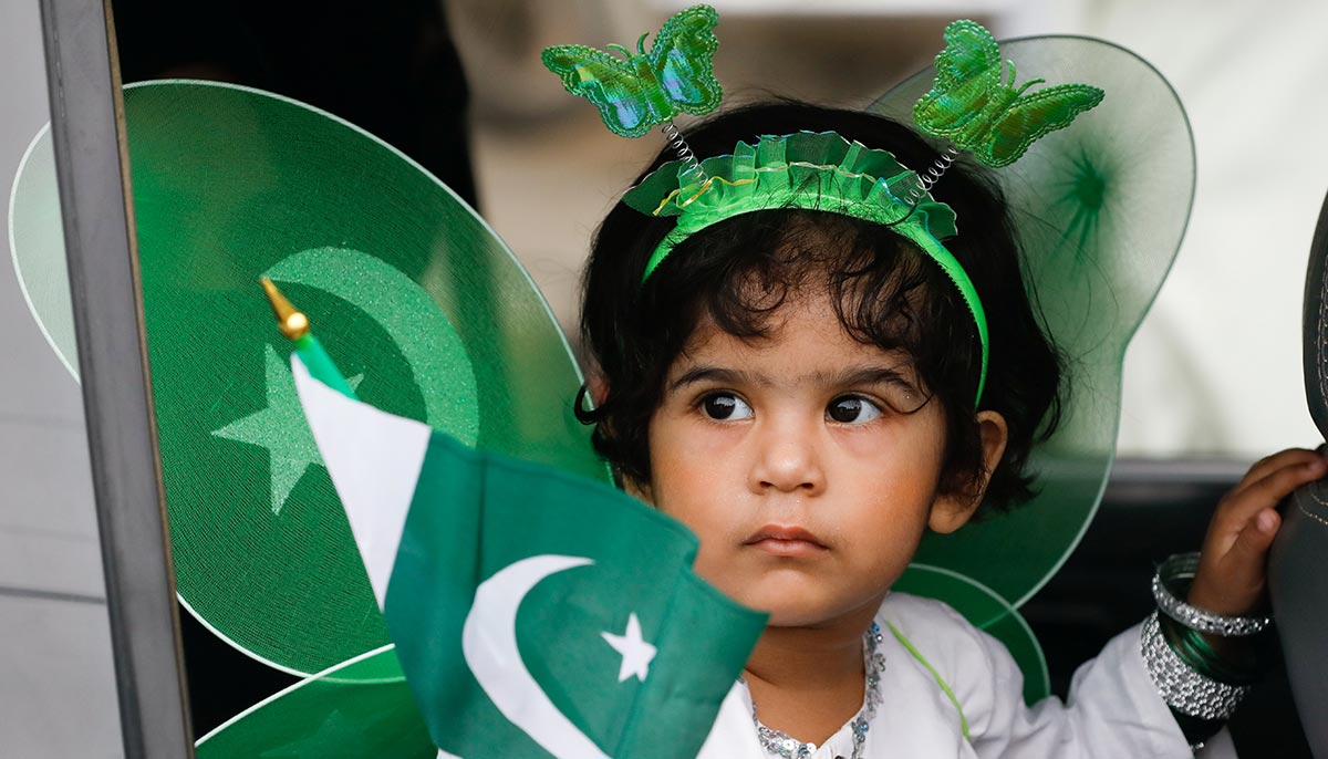 A girl waves a flag from a window of a car during celebrations of Independence Day, in Karachi, Pakistan August 14, 2021. — Reuters/Akhtar Soomro