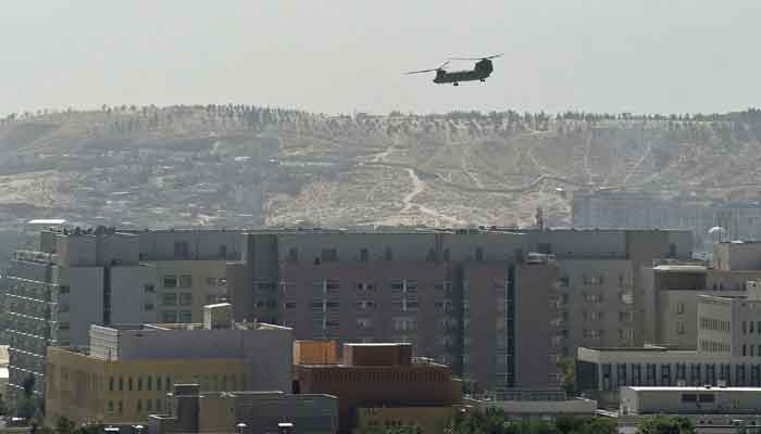 A US military helicopter is pictured flying above the US embassy in Kabul on August 15, 2021. — Photo by Wakil Kohsar/AFP