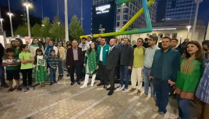 People standing outside the Library of Birmingham which was lit up green and white on the occasion of Pakistan’s 75th Independence Day, on August 14, 2021, in Birmingham, UK. — Photo by authors