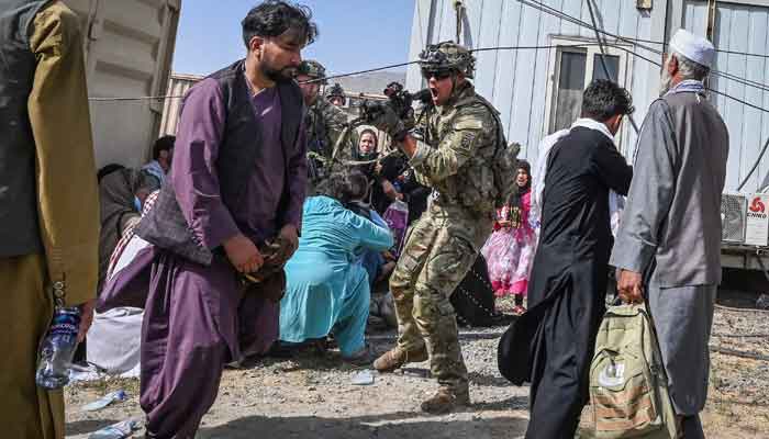 A US soldier (C) point his gun towards an Afghan passenger at the Kabul airport in Kabul on August 16, 2021, after a stunningly swift end to Afghanistans 20-year war, as thousands of people mobbed the citys airport trying to flee the groups rule. — Photo by Wakil Kohsar/AFP