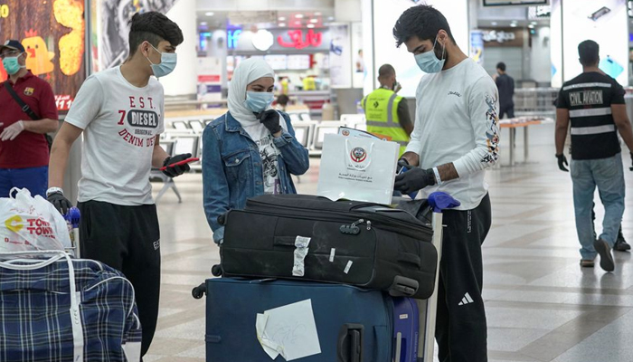Repatriated Kuwaitis from Amman, wearing protective face masks, following the outbreak of the coronavirus disease (COVID-19), prepare their luggage while arriving at Kuwait Airport, Kuwait April 21, 2020. — Reuters/File