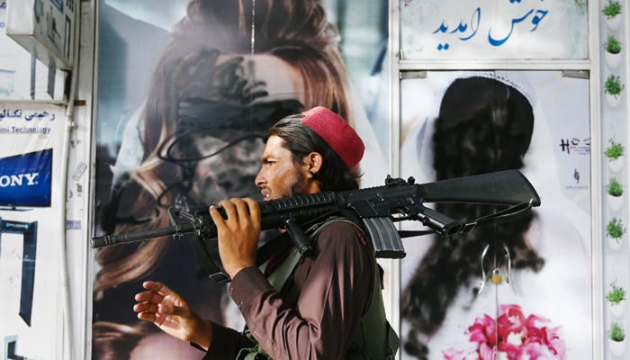 A Taliban fighter walks past a beauty saloon with images of women defaced using a spray paint in Shar-e-Naw in Kabul on August 18, 2021. — AFP/File