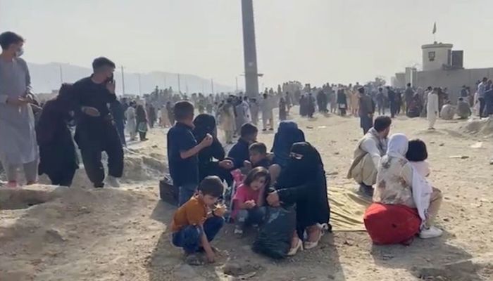People gathered outside the airport react to gunfire, in Kabul, Afghanistan August 18, 2021 in this still image taken from video. ASVAKA NEWS via REUTERS
