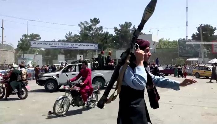 A Taliban fighter runs towards crowd outside Kabul airport, Kabul, Afghanistan August 16, 2021, in this still image taken from a video. Photo Reuters