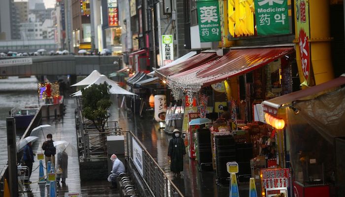 A woman, wearing protective mask following an outbreak of the coronavirus disease (COVID-19), walks on an almost empty street in the Dotonbori entertainment district of Osaka, Japan, March 14, 2020. Photo: Reuters