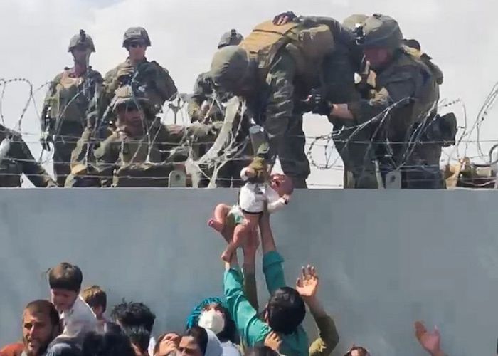 A baby is handed over to the American army over the perimeter wall of the airport for it to be evacuated, in Kabul, Afghanistan, August 19, 2021, in this still image taken from video obtained from social media. Video taken August 19, 2021. Photo: Reuters