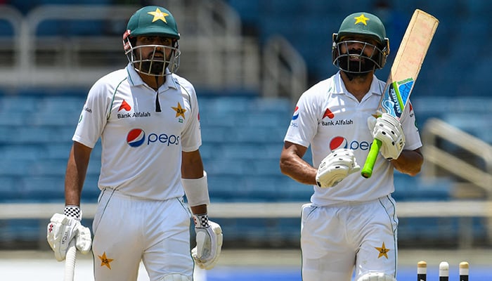 Babar Azam (L) and Fawad Alam (R) of Pakistan walks off the field for the lunch break during day 1 of the 2nd Test between West Indies and Pakistan at Sabina Park, Kingston, Jamaica, on August 20, 2021. — AFP