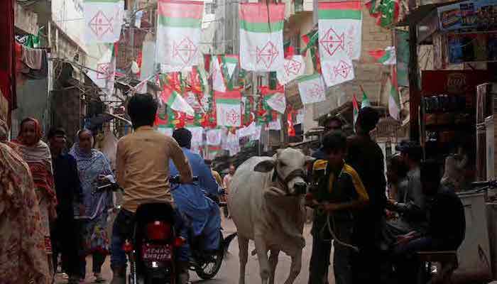 Residents walk along a street decorated with flags of political parties, ahead of general elections in the Lyari neighborhood in Karachi, Pakistan July 9, 2018. Photo: Reuters