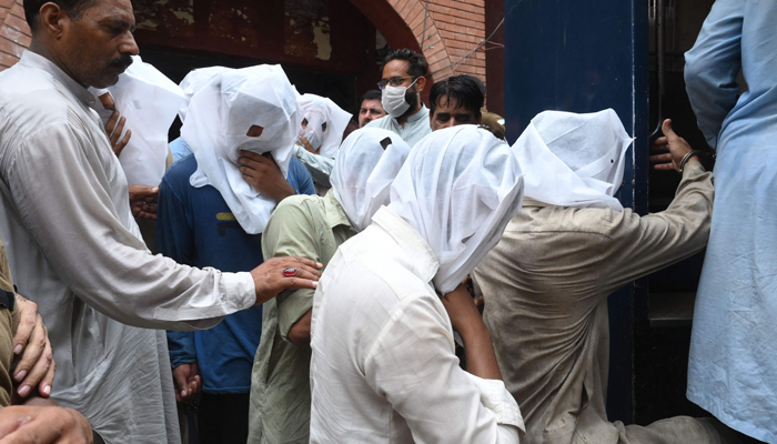Policemen escort men after being presented in a local court for allegedly groping and harassing a female female TikToker in a public park on the eve of Pakistan´s Independence Day, in Lahore on August 21, 2021. — AFP