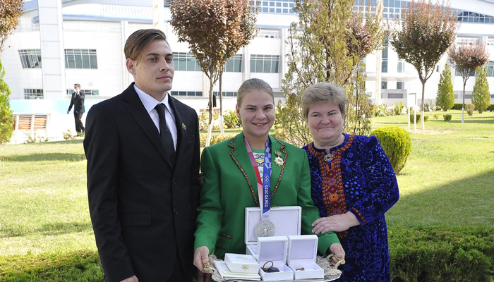 Turkmenistans first-ever Olympic medallist, weightlifter Polina Guryeva (C) poses for pictures with her brother (L) and mother after receiving presents during a ceremony in the capital Ashgabat, on August 21, 2021. Polina Guryeva, was gifted an apartment, a car and $50,000 in cash. — AFP