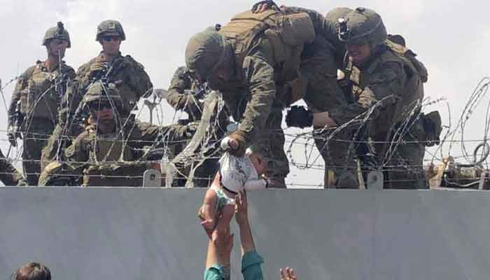 This image taken by Omar Kaidiri and made available to AFP on August 20 shows a US Marine grabbing an infant over a fence of barbed wire during an evacuation at Hamid Karzai International Airport in Kabul on August 19, 2021. — AFP
