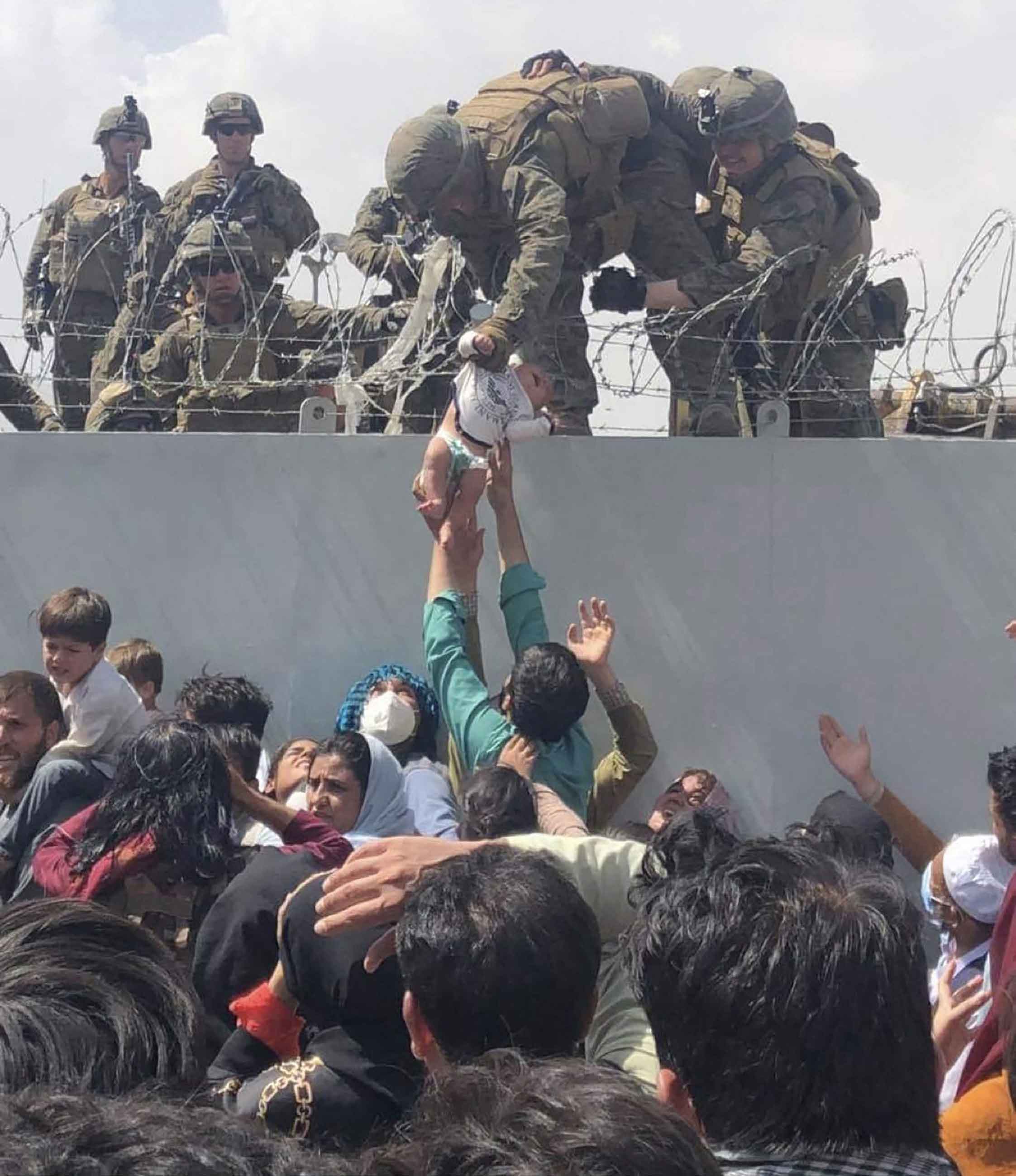 This image taken by Omar Kaidiri and made available to AFP on August 20 shows a US Marine grabbing an infant over a fence of barbed wire during an evacuation at Hamid Karzai International Airport in Kabul on August 19, 2021. — AFP