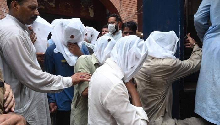 Policemen escort men after being presented in a local court for allegedly groping and harassing a female TikToker in a public park on the eve of Pakistans Independence Day, in Lahore on August 21, 2021. — AFP/File