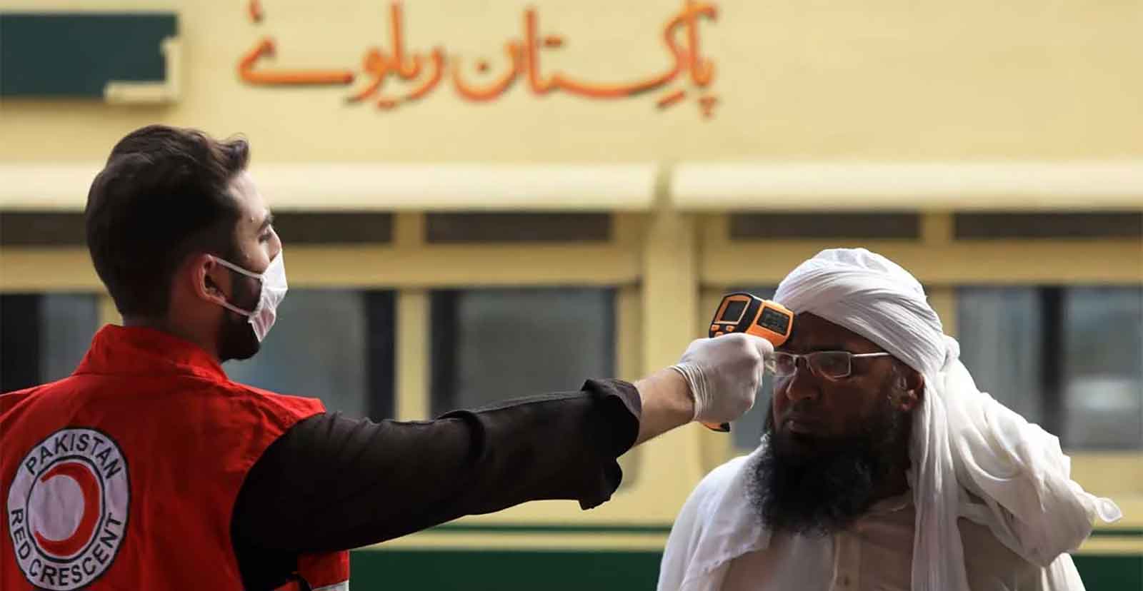 A Pakistan Red Crescent worker checks a man for his temperature using a thermal gun. Photo: AFP