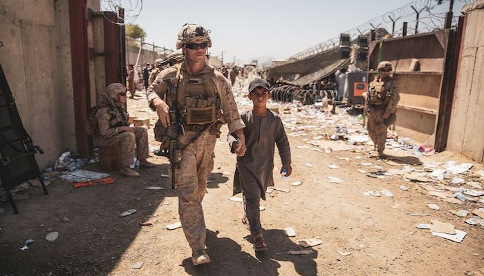 A U.S. Marine with the Special Purpose Marine Air-Ground Task Force-Crisis Response-Central Command (SPMAGTF-CR-CC) escorts a child to his family during an evacuation at Hamid Karzai International Airport in Kabul, Afghanistan, August 24, 2021. Sgt. Samuel Ruiz/U.S. Marine Corps/Handout via REUTERS