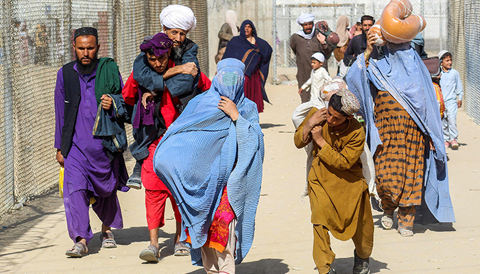 Afghans walk along fences as they arrive in Pakistan through the Pakistan-Afghanistan border crossing point in Chaman on August 24, 2021, following Talibans takeover of Afghanistan. — AFP