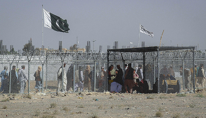 Afghan and Pakistani nationals walk through a security barrier to cross the border at the Pakistan-Afghanistan border crossing point in Chaman on August 24, 2021, following Talibans takeover of Afghanistan. — AFP