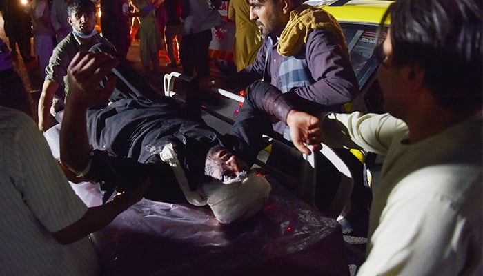 Medical and hospital staff bring an injured man on a stretcher for treatment after two blasts, which killed at least five and wounded a dozen, outside the airport in Kabul on August 26, 2021. — AFP