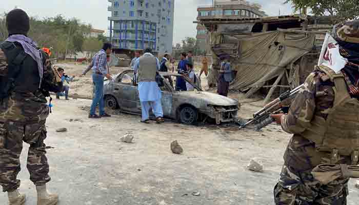 Afghan men take pictures of a vehicle from which rockets were fired, as Taliban forces stand guard, in Kabul, Afghanistan August 30, 2021. -REUTER