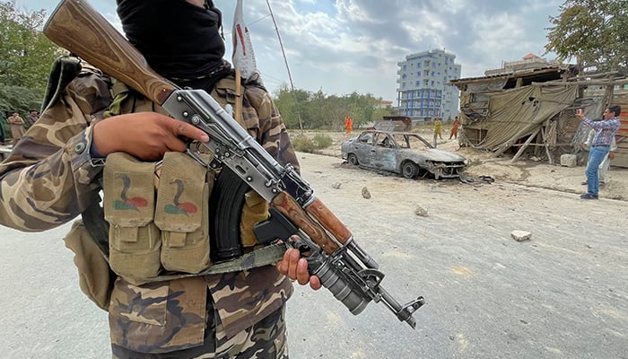 A member of Taliban forces stands guard as Afghan men take pictures of a vehicle from which rockets were fired, in Kabul, Afghanistan August 30, 2021. — Reuters