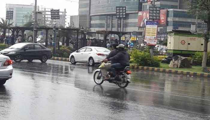 Riders on a motorcycle make their way through slippery roads in Karachi. Photo: Geo.tv/file