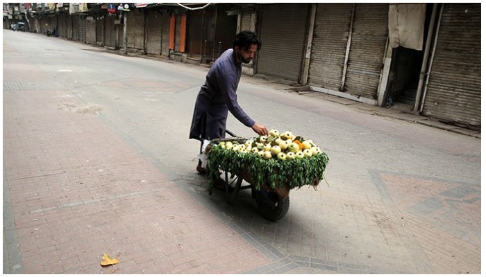 A fruit vendor waits for customers as he sells guava from a wheelbarrow along a closed market during a lockdown, following an outbreak of coronavirus disease (COVID-19), in Lahore, Pakistan. —  AFP