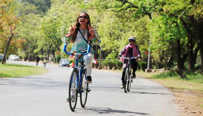 A woman flashes victory signs as she rides a bicycle during Girls on Bike rally in Islamabad, Pakistan, April 2, 2017. Photo: Reuters