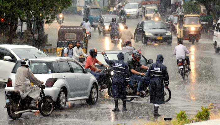 Raincoat-clad traffic police officials guide commuters during heavy downpour, at Saddar, Karachi, on Saturday, September 04, 2021. — Rizwan Ali/PPI Images.